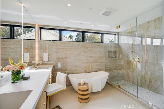 bathroom featuring shower with separate bathtub, vanity, tile patterned floors, and tile walls