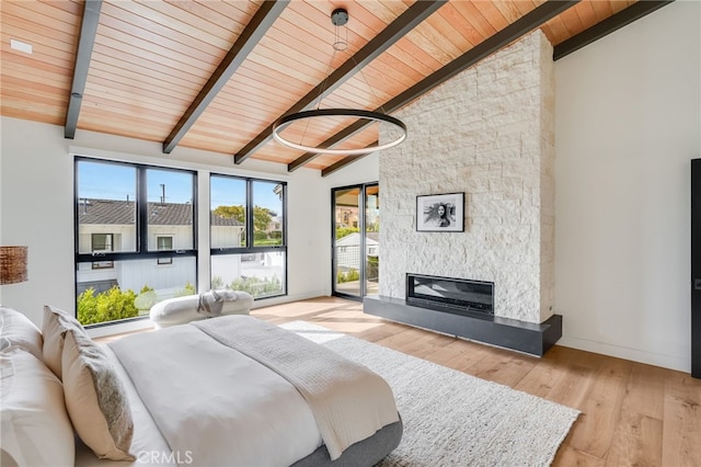 bedroom featuring a stone fireplace, beamed ceiling, wooden ceiling, and light wood-type flooring