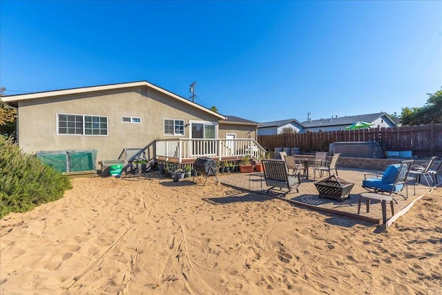 rear view of property featuring a wooden deck and an outdoor fire pit