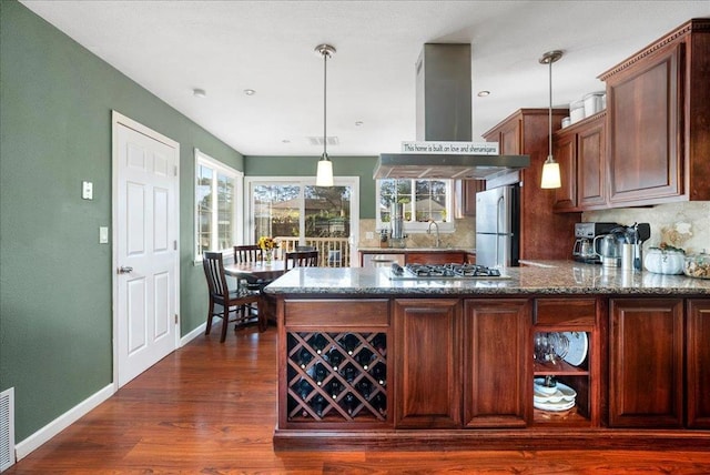 kitchen featuring decorative light fixtures, stainless steel appliances, plenty of natural light, backsplash, and island range hood