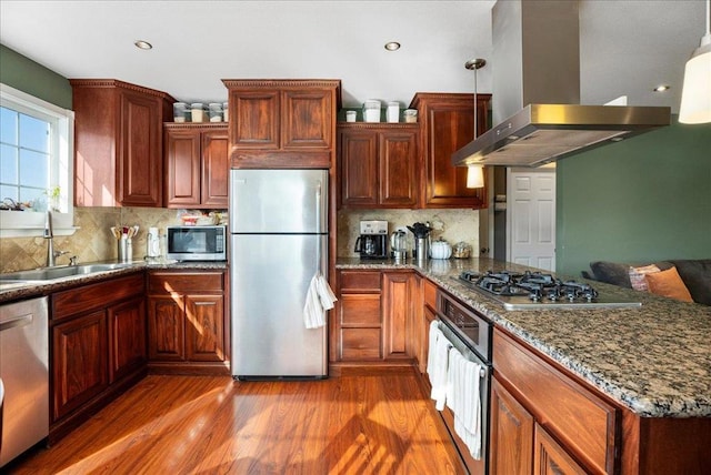 kitchen with pendant lighting, sink, hardwood / wood-style flooring, stainless steel appliances, and island range hood