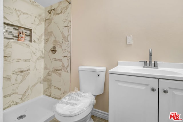 bathroom featuring vanity, toilet, and tiled shower