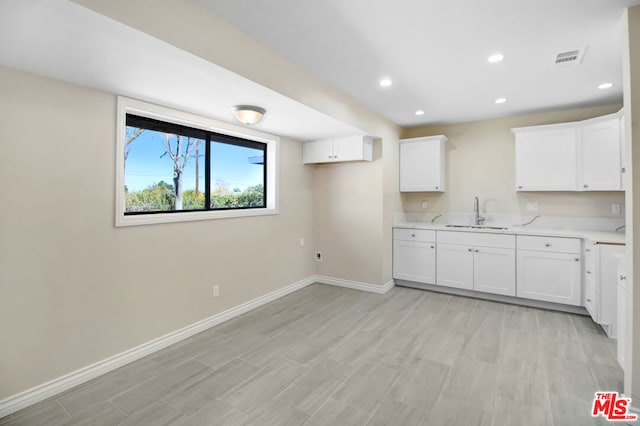 kitchen featuring white cabinets, sink, and light hardwood / wood-style flooring