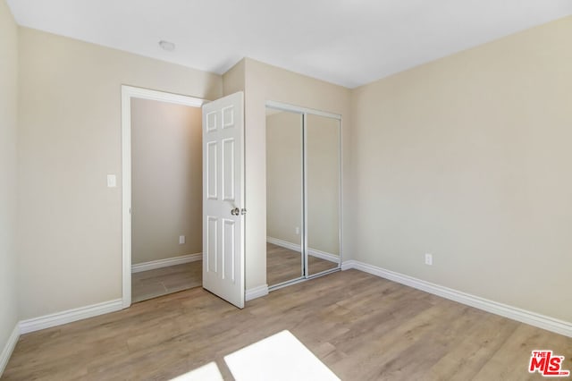 unfurnished bedroom with a closet and light wood-type flooring