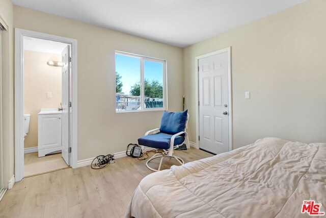 bedroom featuring connected bathroom and light hardwood / wood-style flooring