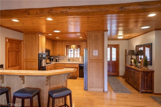 kitchen with tile countertops, light wood-type flooring, and wooden ceiling