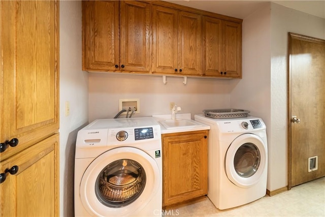 clothes washing area featuring washer and dryer, sink, and cabinets