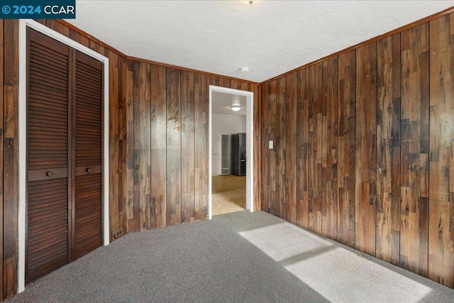 carpeted empty room featuring crown molding and wooden walls