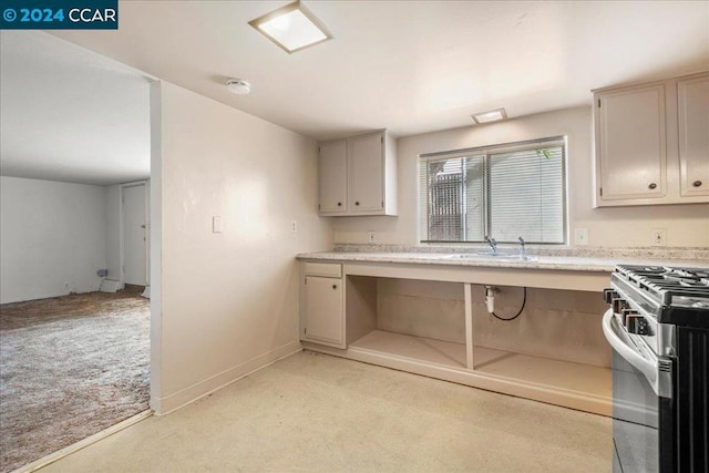 kitchen with light colored carpet, stainless steel gas range oven, and sink