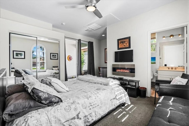 carpeted bedroom with connected bathroom, multiple windows, ceiling fan, and sink