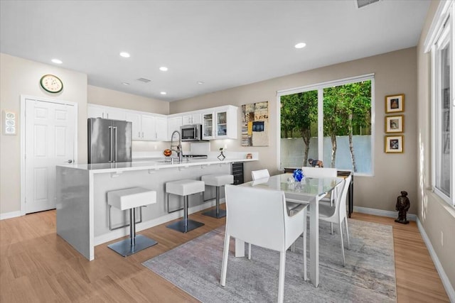 dining space with light hardwood / wood-style floors, sink, and wine cooler