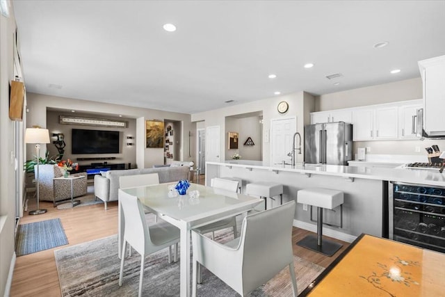 dining space with light hardwood / wood-style flooring, beverage cooler, and sink