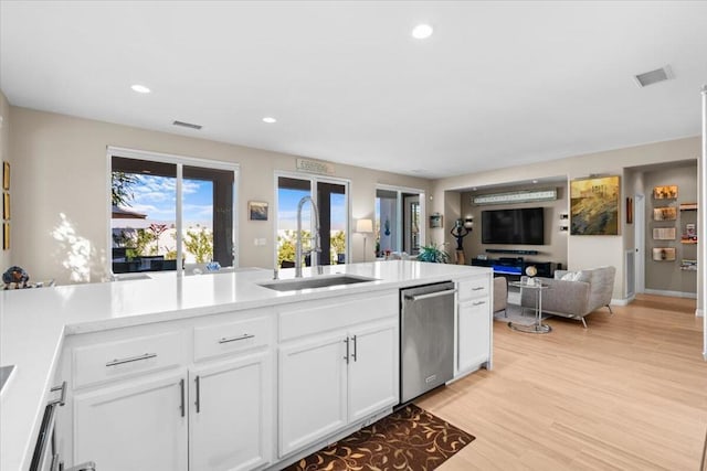 kitchen featuring white cabinetry, sink, stainless steel dishwasher, and light hardwood / wood-style floors