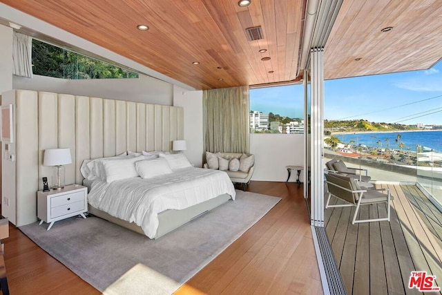 bedroom featuring multiple windows, hardwood / wood-style floors, a water view, and wooden ceiling