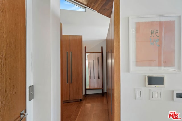 corridor with light hardwood / wood-style floors, vaulted ceiling, and wood ceiling