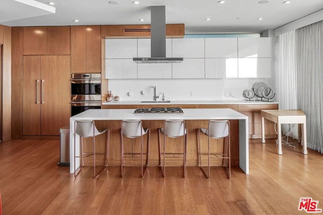 kitchen with white cabinets, light wood-type flooring, stainless steel appliances, and a spacious island