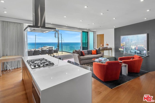 kitchen with stainless steel gas stovetop, a water view, a kitchen island, light hardwood / wood-style floors, and extractor fan