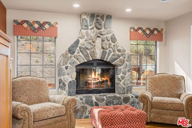 sitting room featuring a stone fireplace and wood-type flooring