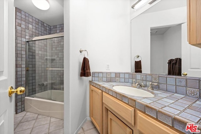 bathroom featuring tile patterned flooring, vanity, and enclosed tub / shower combo