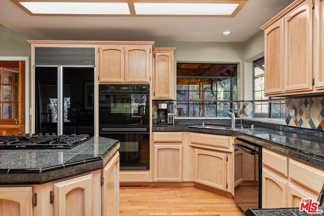 kitchen with sink, light brown cabinets, light hardwood / wood-style flooring, backsplash, and black appliances