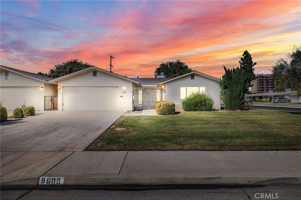 single story home featuring a lawn and a garage