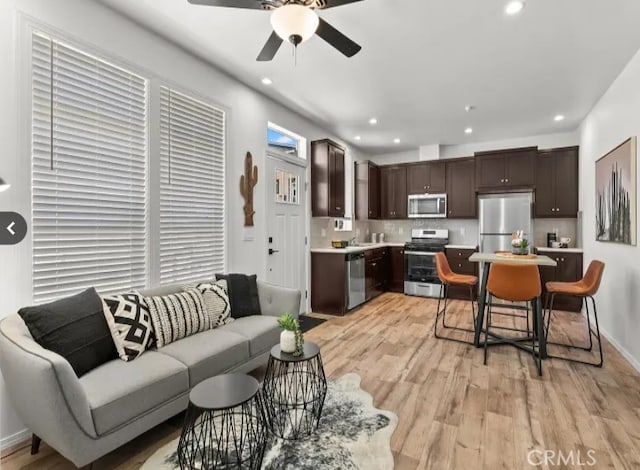 living room with a ceiling fan, recessed lighting, baseboards, and light wood finished floors