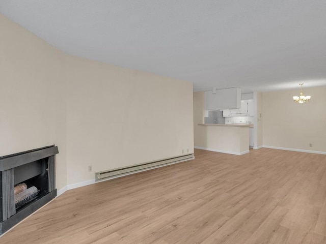 unfurnished living room with baseboard heating, light hardwood / wood-style flooring, and a notable chandelier