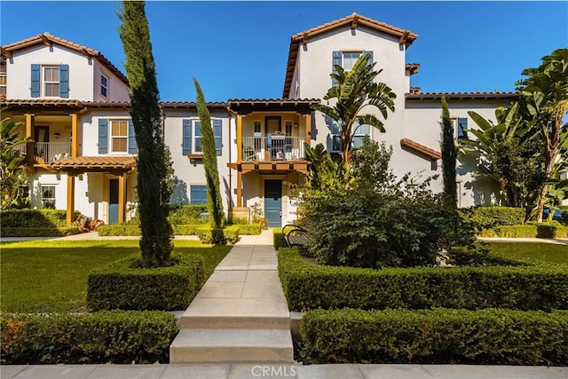 mediterranean / spanish house with a balcony and a front lawn