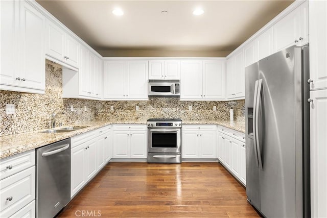 kitchen featuring white cabinetry, sink, stainless steel appliances, light stone counters, and dark hardwood / wood-style floors