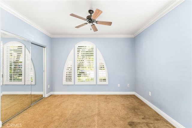 carpeted empty room with ceiling fan, a healthy amount of sunlight, and ornamental molding