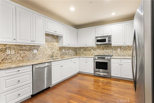 kitchen with white cabinets, stainless steel appliances, and light hardwood / wood-style flooring