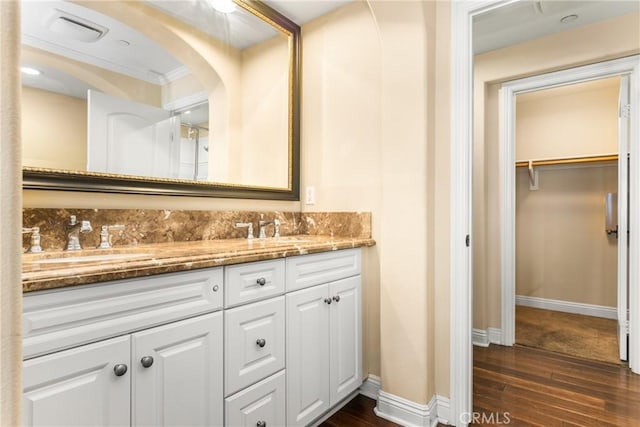 bathroom with wood-type flooring, vanity, and crown molding