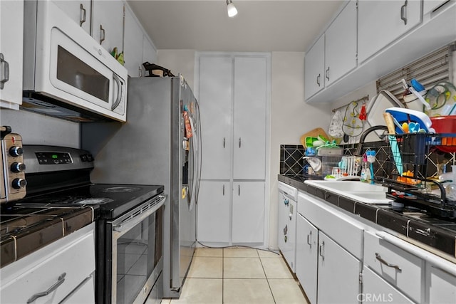 kitchen featuring white cabinetry, light tile patterned flooring, electric stove, and sink