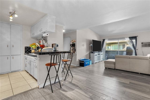 806 Coriander Dr Unit G, Torrance, CA 90502 - kitchen with open floor plan, light wood finished floors, white cabinets, ornamental molding, and a wall unit AC