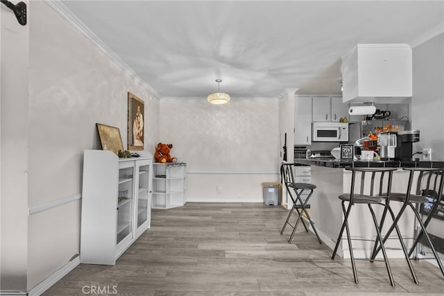 806 Coriander Dr Unit G, Torrance, CA 90502 - kitchen featuring white microwave, crown molding, dark countertops, a breakfast bar area, and wood finished floors