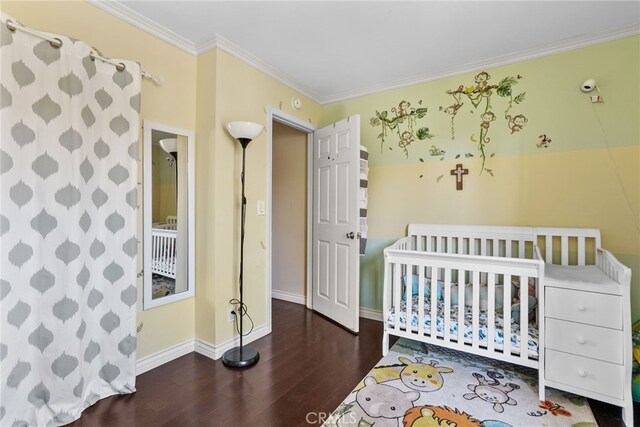 bedroom featuring dark hardwood / wood-style flooring, a nursery area, and crown molding