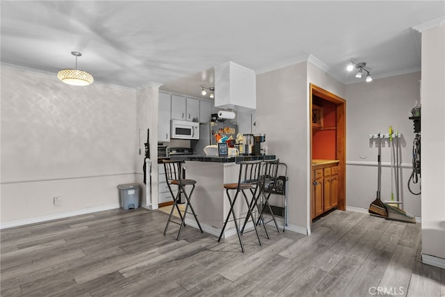 kitchen featuring a kitchen bar, light hardwood / wood-style floors, white cabinetry, and crown molding