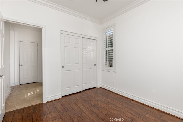 unfurnished bedroom with a closet, dark hardwood / wood-style flooring, and ornamental molding