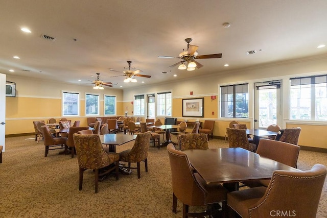 carpeted dining space with ceiling fan and ornamental molding