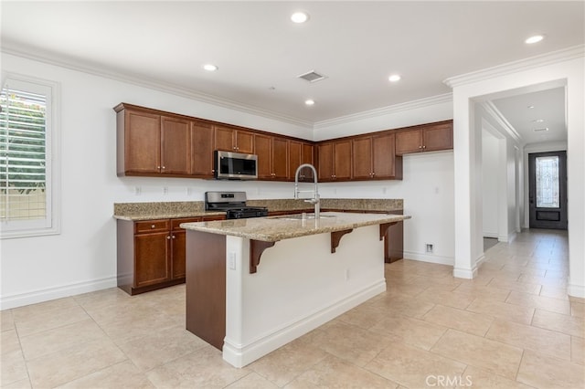 kitchen with a kitchen bar, sink, an island with sink, light stone counters, and stainless steel appliances