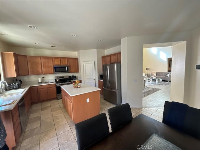 kitchen with sink, a center island, light tile patterned floors, and appliances with stainless steel finishes