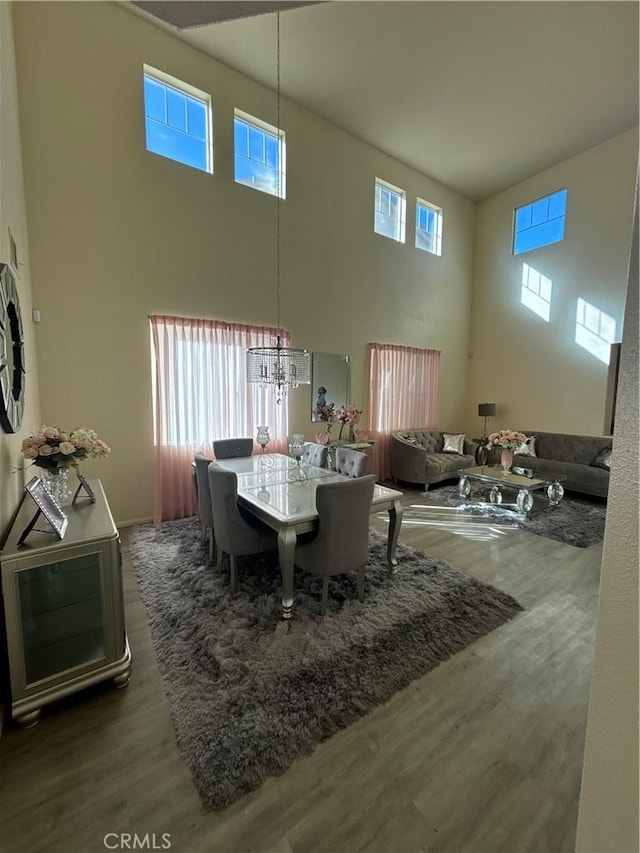 dining space featuring a chandelier, a towering ceiling, dark hardwood / wood-style floors, and a wealth of natural light