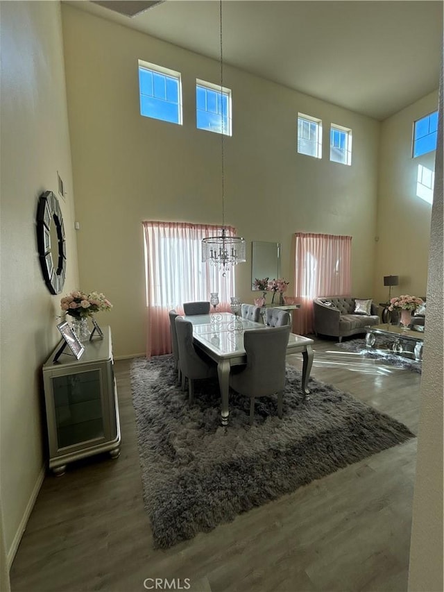 dining area featuring wood-type flooring, a high ceiling, and a chandelier