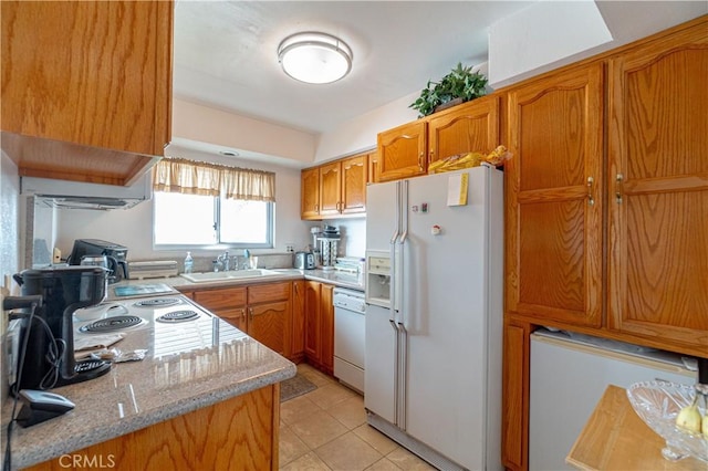 kitchen with light tile patterned floors, light stone countertops, sink, and white appliances