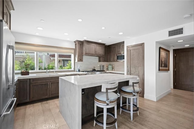 kitchen with sink, a center island, light hardwood / wood-style floors, and appliances with stainless steel finishes