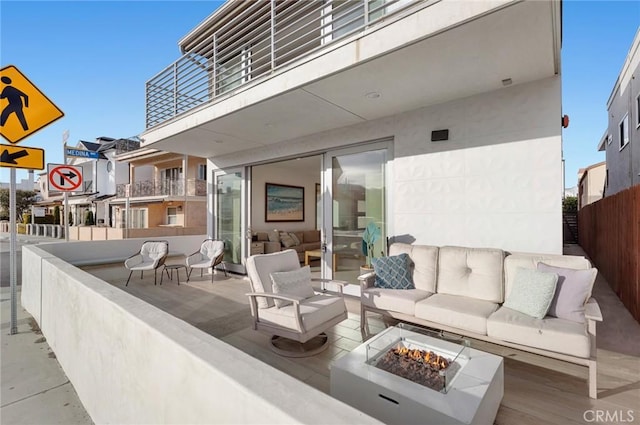 view of patio featuring a balcony and an outdoor living space with a fire pit