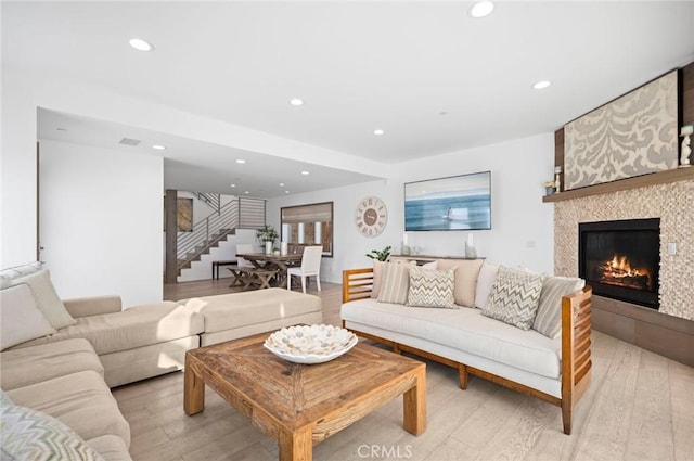 living room featuring a tiled fireplace and light hardwood / wood-style flooring