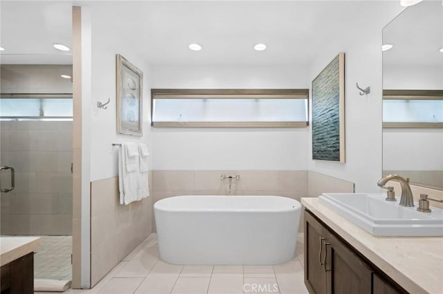 bathroom featuring tile patterned floors, vanity, independent shower and bath, and tile walls