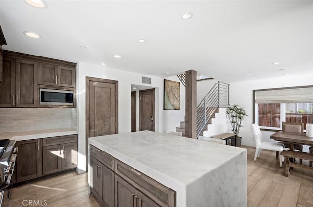 kitchen with a center island, light wood-type flooring, stainless steel appliances, and backsplash