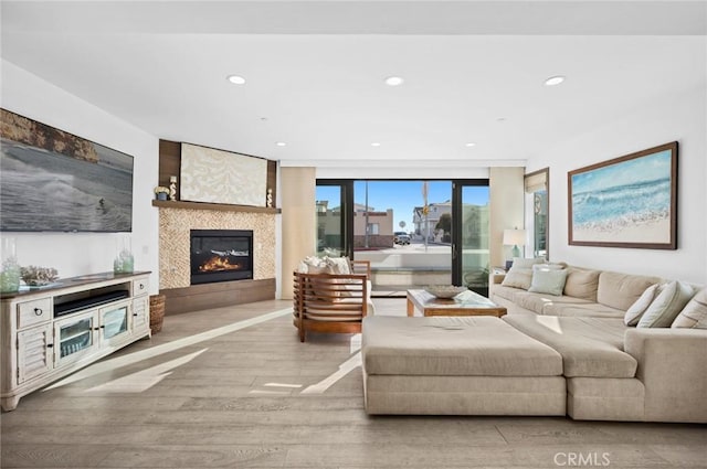 living room featuring expansive windows, light wood-type flooring, and a tile fireplace